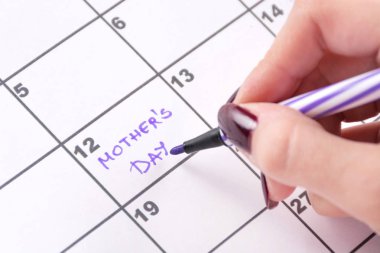 Kız elle mor keçeli kalem takvim sözcükleri anneler günü hatırlatma tatil için yazma. Yakın, seçici odak