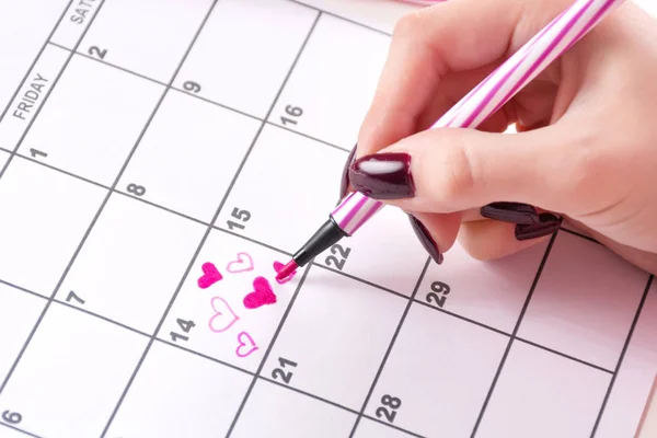 Woman hand drawing and paint heart in calendar with felt pen for Valentines day. Love and Valentines day holiday concept. Close up, selective focus