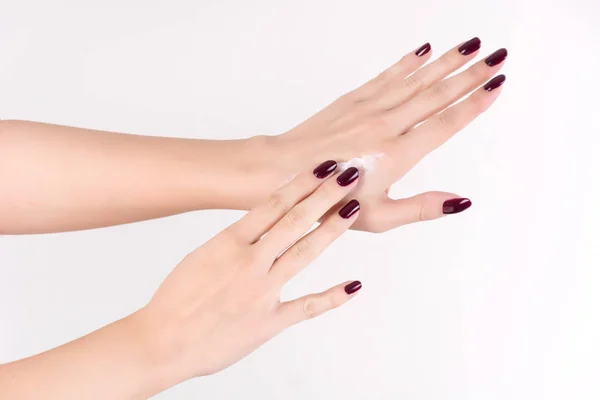 Gentilmente Mãos Mulher Com Manicure Vinho Tinto Aplicando Creme Mão — Fotografia de Stock