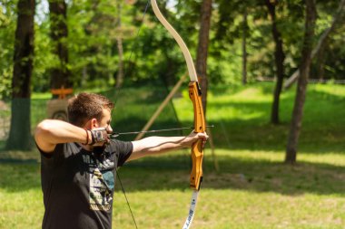 Niş, Sırbistan - 16 Haziran. 2019: Şövalye festivali ve turnuvasında ormanda ok atışı olan genç okçu. Bowman longbow çekim den önce. Yakın çekim, seçici odak