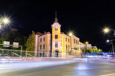Nis, Serbia - August 24, 2019: The old and retro courthouse and lights lines form fast car on the street at night in the city of Nis, Serbia. Long exposure concept and blurred motion clipart