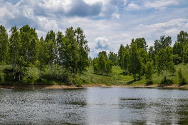 Dalgalı mavi suyu olan dağ gölü ve bulutlu bir yaz gününde ormanlı yeşil çayır. Seyahat, turizm ve doğa konseptinde tatil. Vlasina Gölü, Sırbistan, Avrupa.