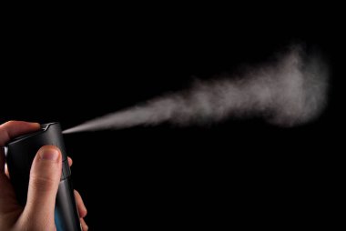 Eldeki sprey kutusu ve beyaz renkli aerosol siyah arkaplanda izole edilmiş, kapat