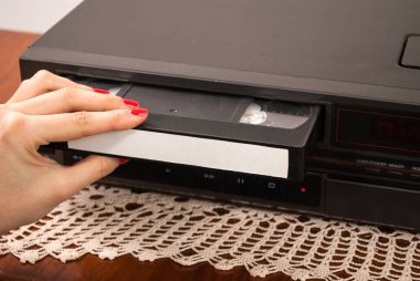 Kız eli eski video kayıt cihazına boş VHS kaset yerleştiriyor.