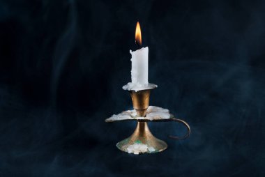 Eski şamdandaki mum ve arka plandaki duman koyu arkaplanda izole edilmiş.