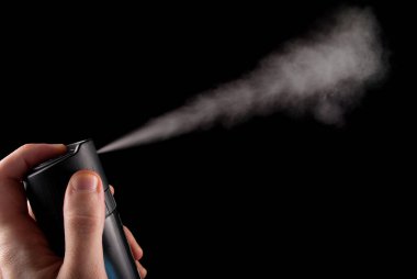 Elinde deodorant spreyi ve siyah arka planda izole edilmiş beyaz sprey, kapat.