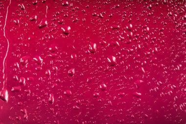 Renkli arka planda bir damla su. Pembe. Yüzeyin derinliği. Seçici odaklanma. Ayarlanmış