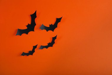 Turuncu arka planda uçan dört yarasa şekli ve dizayn için alan. Cadılar Bayramı konsepti