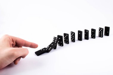 Domino taşlarını iterek stüdyodaki beyaz arka planda izole bir şekilde düşerler. Domino etkisi