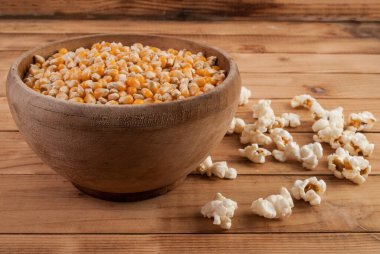 Kasede çiğ mısır tohumu ve tahta masada patlamış mısır.