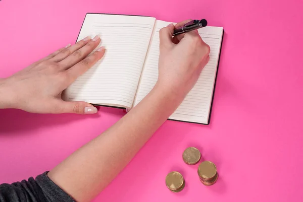 Женщина Держит Ручку Руке Пишет Рядом Монетой Розовом Фоне — стоковое фото