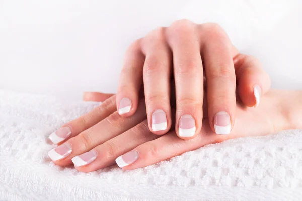 Hands with french nails manicure on white towel