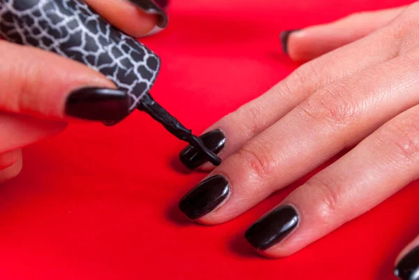 Menina Jovem Aplicando Gel Esmalte Preto Próprio Fundo Vermelho Com — Fotografia de Stock