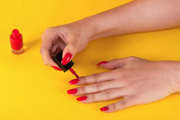 Chica Aplicando Esmalte Uñas Rojo Aislado Sobre Fondo Amarillo —  Fotos de Stock