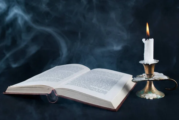 ろうそくの棒で燃焼し 暗い黒の手招きに古い本や煙を開くキャンドル — ストック写真