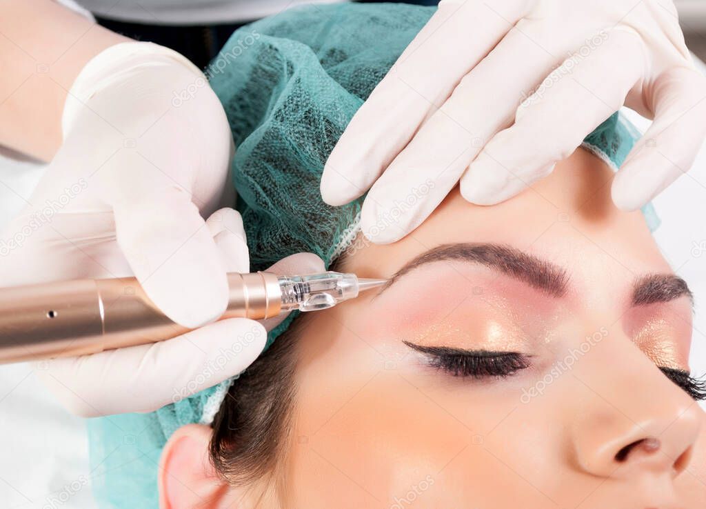 Applying permanent Makeup for Eyebrows. Beautician Doing Eyebrow Tattooing For Female Face