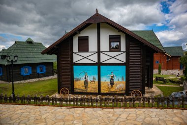 Zlatibor, Vodice, Sırbistan - 26 Temmuz. Geleneksel ev ve El Paso şehrinde eski Sırp tarzında dramatik bir gökyüzü. Sırp tematik parkı. Seyahat kavramı