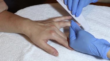 Güzellik uzmanı güzellik salonunda bir kızın tırnaklarını törpülüyor.