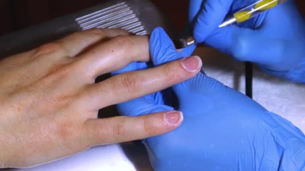 Beautician mengaplikasikan gel mantel dengan kuas tangan gadis di salon kecantikan — Stok Video