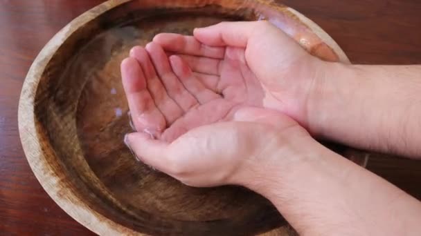 L'homme met ses mains dans un bol d'eau en bois et attrape l'eau dans ses poings — Video