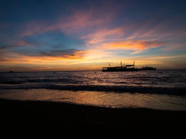 Filipinler 'de plajda gün doğumu. Dalgıçlar sabah erkenden dalmayı bekliyor..