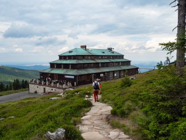 Karpacz / Polonya - 24.07.2020. Karkonosze Ulusal Parkı 'ndaki Dağ Barınağı. İnsanlar terasta ve patikada.