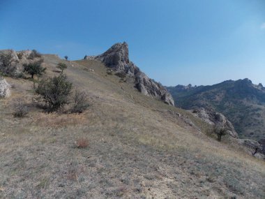 Parlak mavi gökyüzüne karşı dağların yamaçlarının manzarası.