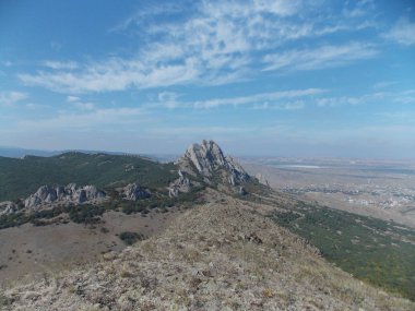 Dağ ve kasaba üzerinde bulutlar ile parlak mavi gökyüzü görünümü.