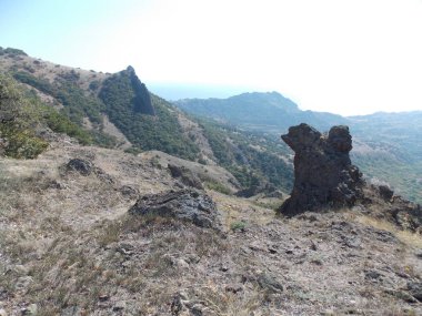 Dağların yeşil yamaçlarına karşı bir kaya görünümü.