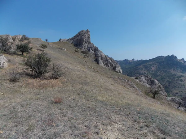 Parlak mavi gökyüzüne karşı dağların yamaçlarının manzarası.