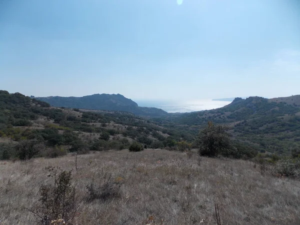 Dağların yakınında denizde güneşin yansıması görünümü.