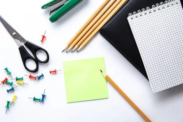 Stationery. Background of school or office accessories. Note, pencil, scissors, push pins, sticker for notes, stapler on white desk. Success and creative concept. Idea of a diligent study or work