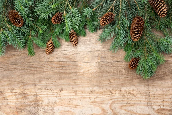 Christmas card with space for text. Green pine and spruce branches and cones on rustic aged wooden background. Frame — Stock Photo, Image