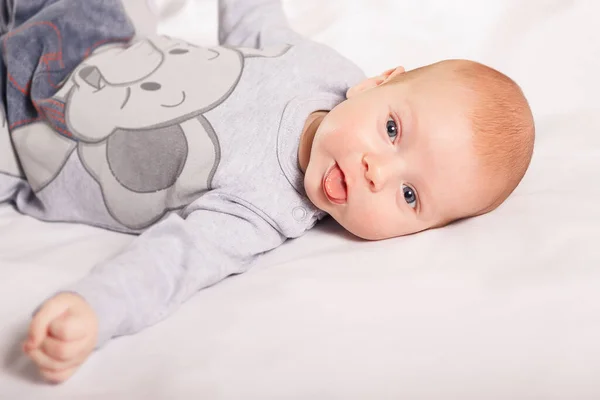 Niño recién nacido sonríe se encuentra en el interior de fondo blanco. Feliz, lindo y bonito. Cuidado en el hogar y acogedor. Maternidad —  Fotos de Stock