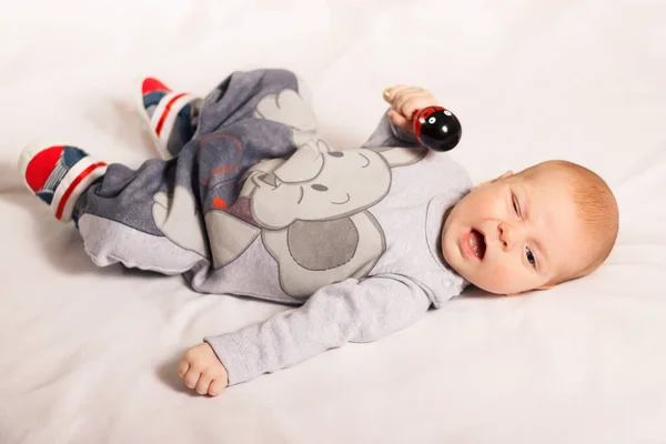 Niño recién nacido sonríe se encuentra con el juguete en el interior de fondo blanco. Feliz, lindo y bonito. Cuidado en el hogar y acogedor. Maternidad —  Fotos de Stock