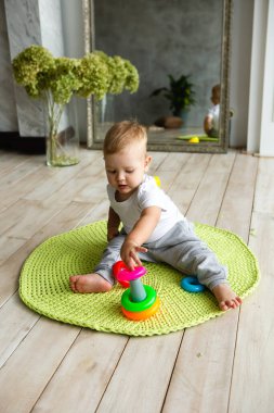 Küçük çocuk, oyuncak piramitle kaplanmış, ahşap zeminde örülmüş karpuz çiziyor. İç kısımda örgü tarzı. Sıcak ve samimi. Oyuncu çocuklar.