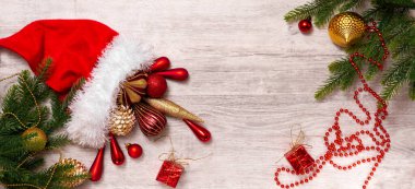 Noel Baba şapkası ve noel süsleri: koni, toplar, bant, boncuklar, hediye kutusu ve ahşap zemin üzerinde Noel ağacı. Kopyalama. Yeni yılın en üst görünümü.