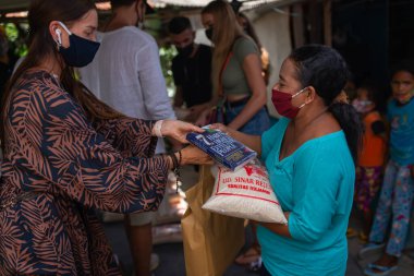 Benoa, Kuta, Kabupaten Badung, Bali, Endonezya - 8 Temmuz 2020: Endonezya 'da maskeli insanların olduğu küçük bir köyün videosu
