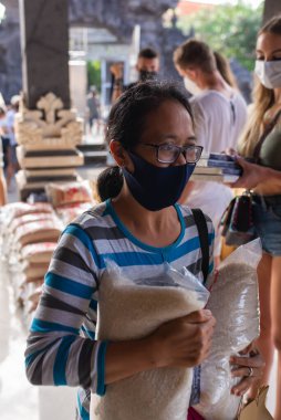 Benoa, Kuta, Kabupaten Badung, Bali, Endonezya - 8 Temmuz 2020: Endonezya 'da maskeli insanların olduğu küçük bir köyün videosu