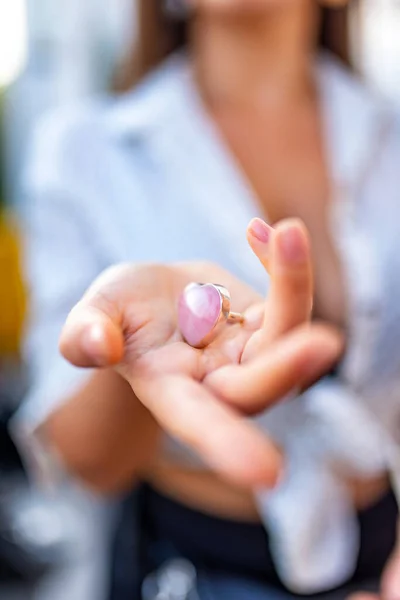 a girl\'s hand with a rose quartz ring shows her heart-shaped jewelry on the pal