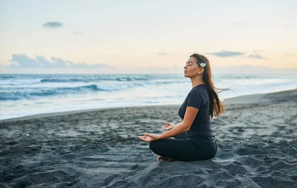 Женщина Практикует Йогу Медитацию Позе Лотоса Черном Пляже Фоне Заката — стоковое фото