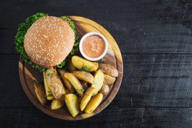 Ahşap tahta üzerinde kızarmış patates ile lezzetli burger
