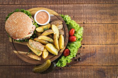 Ahşap tahta üzerinde kızarmış patates ile lezzetli burger