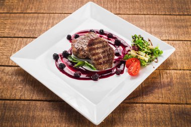 Ahşap arka plan üzerinde raspberrie soslu et biftek ızgara