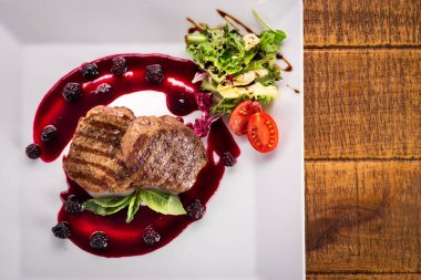 Ahşap arka plan üzerinde raspberrie soslu et biftek ızgara