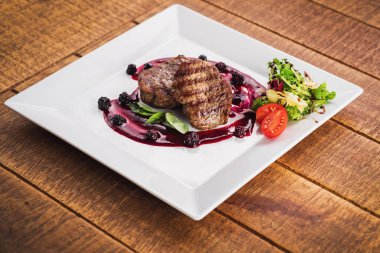 Ahşap arka plan üzerinde raspberrie soslu et biftek ızgara