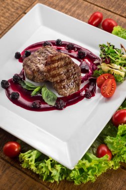 Ahşap arka plan üzerinde raspberrie soslu et biftek ızgara