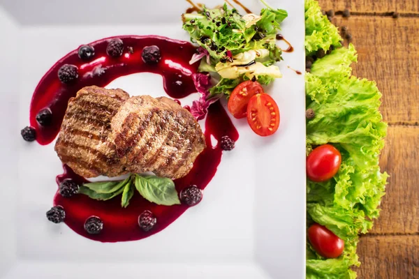 Ahşap arka plan üzerinde raspberrie soslu et biftek ızgara
