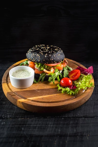 Somon ahşap arka plan üzerinde siyah lezzetli burger
