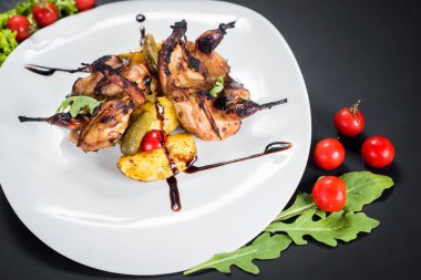 Siyah arka plan üzerine sebzeli ızgara bıldırcın eti